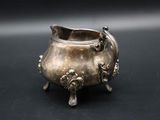 an old silver pot on a black surface with a black background