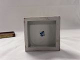 a small white box with a blue flower inside of it
