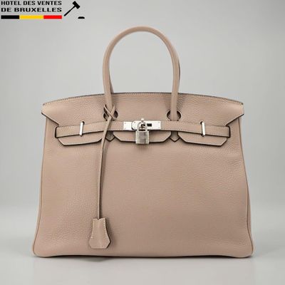 un sac à main en cuir beige muni d'un fermoir métallique sur la poignée