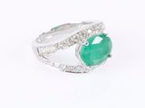 a close up of a ring with a green stone surrounded by diamonds