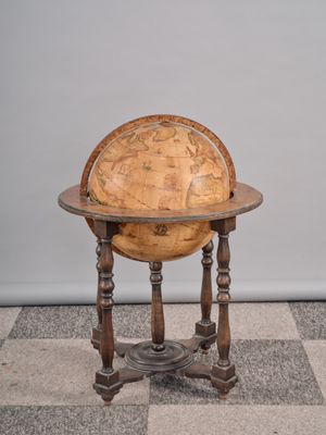 un vieux globe en bois posé sur un socle, au milieu d'un sol à damier