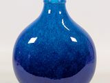 un vase bleu posé sur une surface blanche