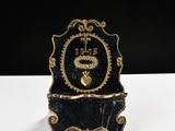 an image of a black and gold clock sitting on top of a white table