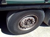 a green truck with a flat tire parked on the side of the road