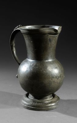 a silver pitcher sitting on a table with a black background