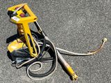a yellow spray gun sitting on the ground next to a hose