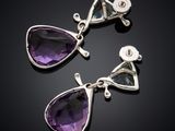 a pair of amethorate and diamond earrings on a black surface