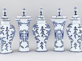 four blue and white vases are lined up against a gray background