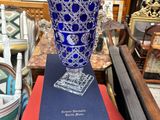 un vase bleu posé sur une boîte, elle-même posée sur une table
