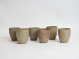 four small cups are lined up in a row on a white surface