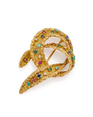 un gros plan sur une broche en or sertie de pierres multicolores