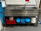 une cuisine équipée d'un évier en inox et d'un tuyau d'eau bleu
