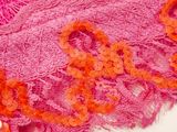 a close up of a pink scarf with orange flowers on it