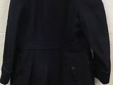 a black coat hanging on a wall with a white brick wall in the background