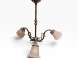 un lustre ancien en laiton avec des abat-jours en verre rose