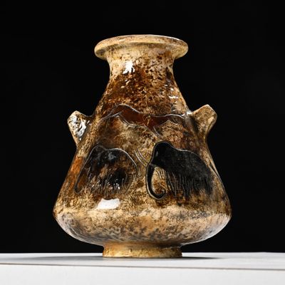 un vase marron orné d'un visage, posé sur une table