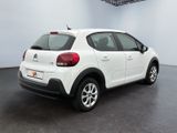 the back of a white car in a room with a black floor