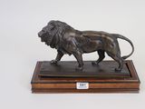 bronze statue of a lion on a wooden base on a white background