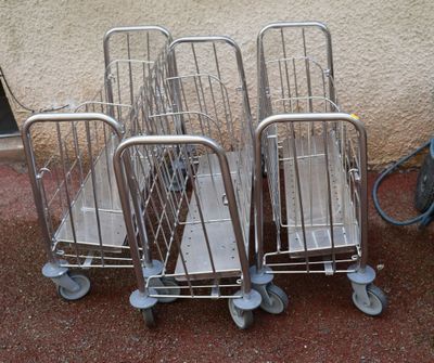 three silver shopping carts sitting next to each other in front of a wall