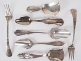 a lot of silver spoons and forks on a white surface