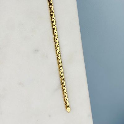 un gros plan d'un collier à chaîne en or posé sur une surface en marbre