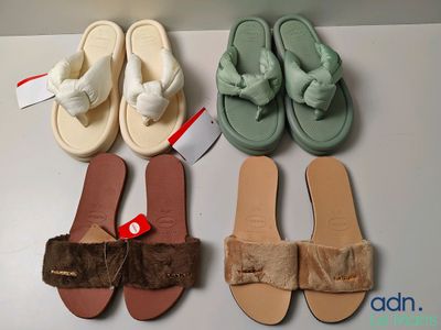 four pairs of slippers are lined up on a white surface