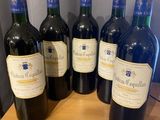 six bottles of red wine are lined up on a table