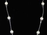 a white pearl and silver necklace on a black background