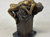 bronze statue of a woman reclining on a rock