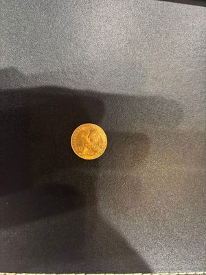 a gold coin sitting on top of a black table next to a window