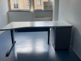 un bureau dans un coin d'une pièce, avec une fenêtre en arrière-plan