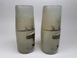 two tall glass vases that have a picture of a boat on them