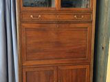 une grande armoire en bois surmontée d'une porte vitrée