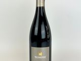 a bottle of red wine sitting on top of a white table