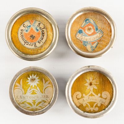 four small tins with different designs on them on a white surface