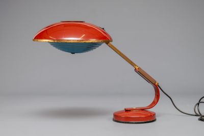 une image représentant une lampe de bureau rouge et bleue posée sur une surface blanche