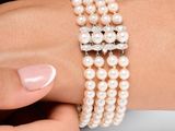 une personne portant un bracelet orné de perles et une bague en diamant au poignet