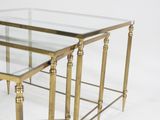 three gold metal and glass nesting tables on a white background