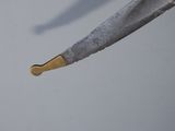 a knife with a gold handle on a gray surface