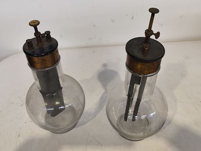 deux bocaux en verre munis de poignées métalliques posés sur une table blanche