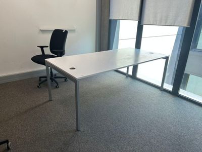 un bureau blanc avec une chaise noire dans une pièce vide