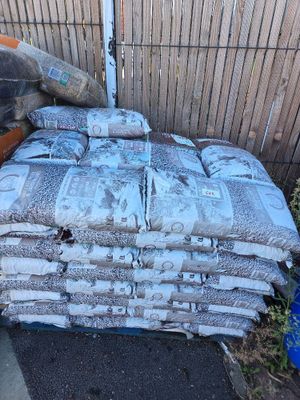 a pile of bags of cement next to a fence