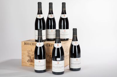 six bouteilles de vin rouge sont posées devant une caisse en bois