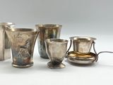 cinq tasses et cuillères en argent posées sur une table
