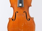 an old violin hanging from a string on a white wall