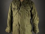 a green jacket on a mannequin stand against a black background