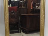 un grand miroir à cadre doré au motif ouvragé dans une pièce