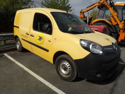 une camionnette jaune garée sur un parking, avec un tracteur en arrière-plan