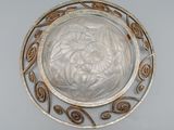 an image of a silver plate with a circular design on it