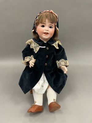 poupée en porcelaine représentant une petite fille vêtue d'un manteau bleu et d'un pantalon blanc